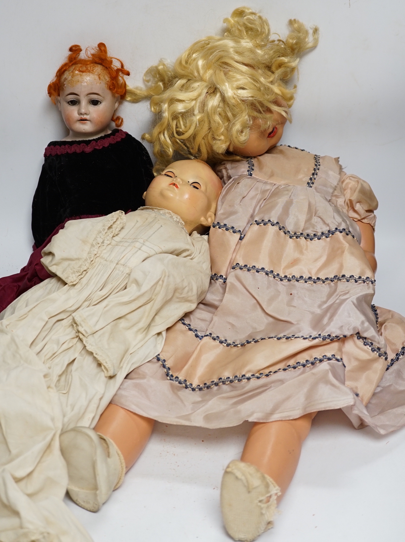 Three dolls; a German Bisque shoulder head doll with sleeping eyes with jointed kid leather body, 46cm, an English celluloid doll and another